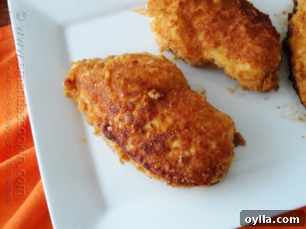 A close up photo of oven fried chicken breasts on a white plate.