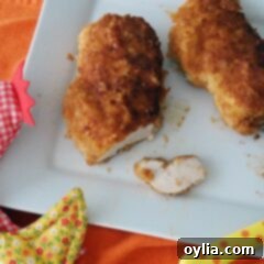 An overhead photo of two oven fried chicken breasts on a white plate.