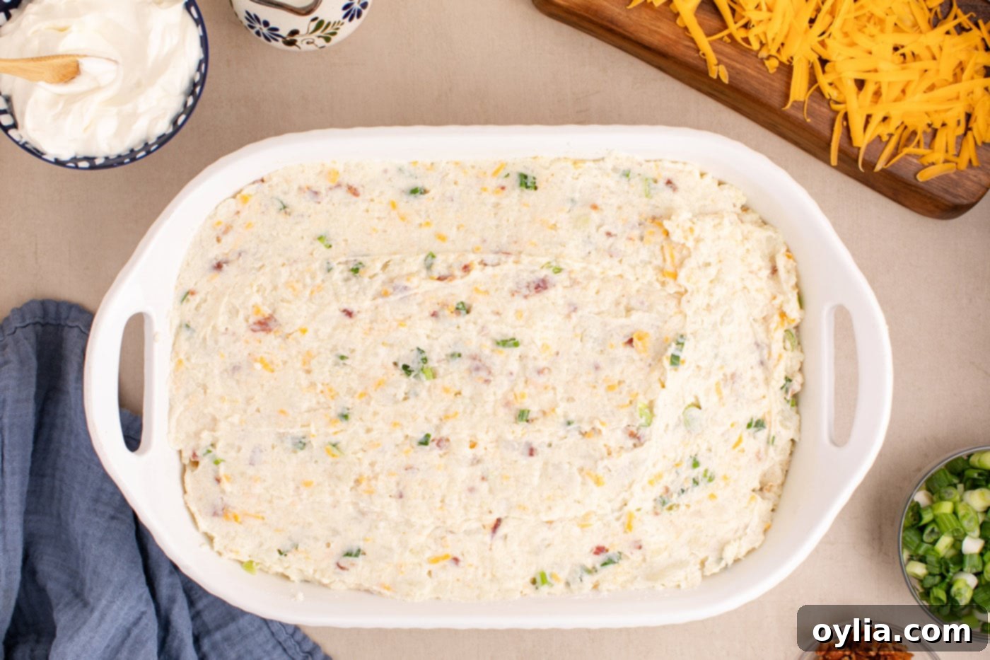 Overhead view of the creamy twice baked potato casserole mixture spread evenly in a 9x13-inch baking dish.