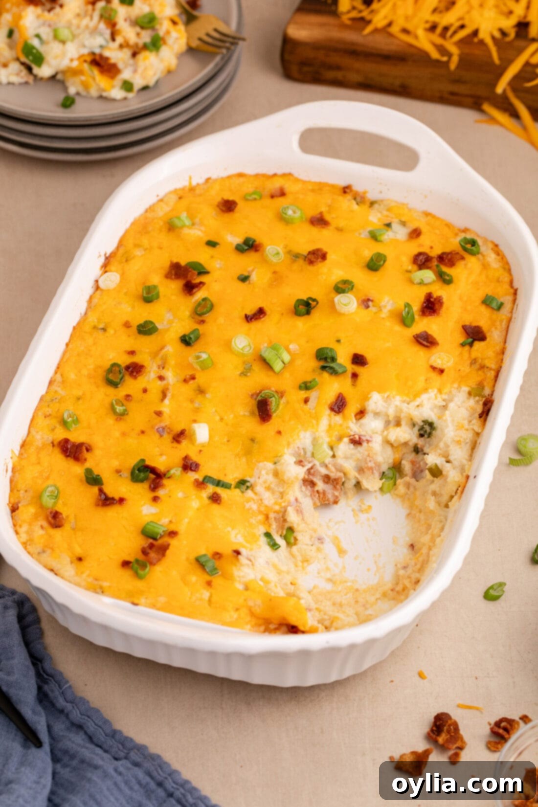 Ultimate Cheesy Potato Bake 14 Twice Baked Potato Casserole with a serving removed, showing its creamy layers and loaded fillings.
