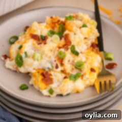 Ultimate Cheesy Potato Bake 15 Twice Baked Potato Casserole on a plate, garnished with bacon and green onions.