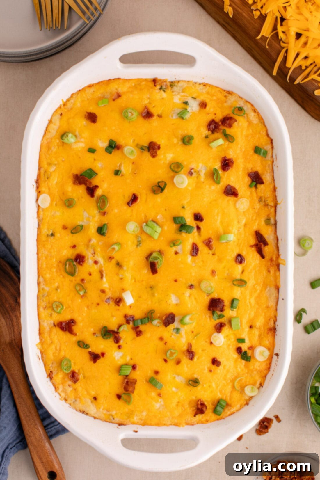 Ultimate Cheesy Potato Bake 3 Overhead photo of a golden-brown Twice Baked Potato Casserole, topped with melted cheese, bacon, and green onions.