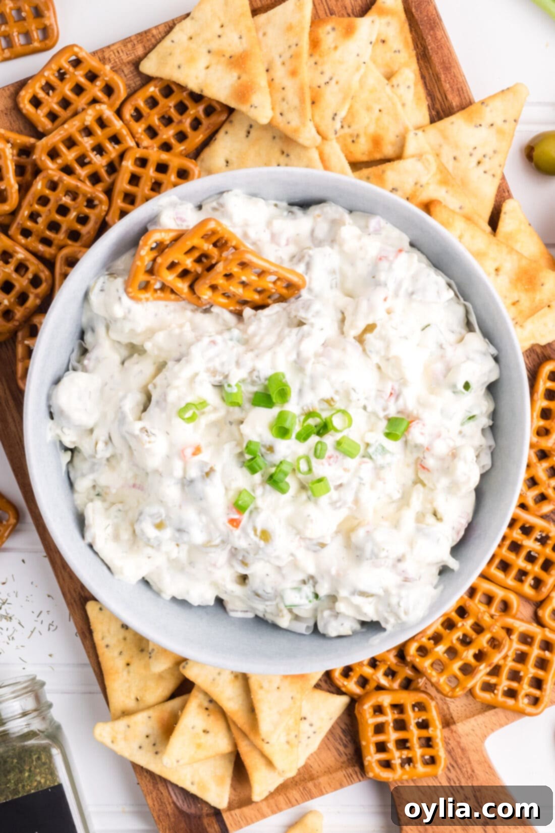 Signature Dirty Martini Dip 2 Overhead photo of a bowl of Dirty Martini Dip, garnished with green onions and a few whole olives