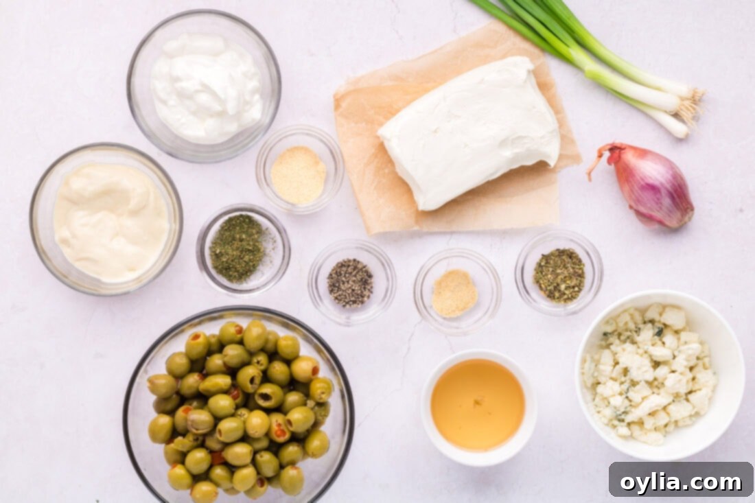 Signature Dirty Martini Dip 4 Ingredients for Dirty Martini Dip arranged on a cutting board including olives, blue cheese, cream cheese, mayo, sour cream, and spices.