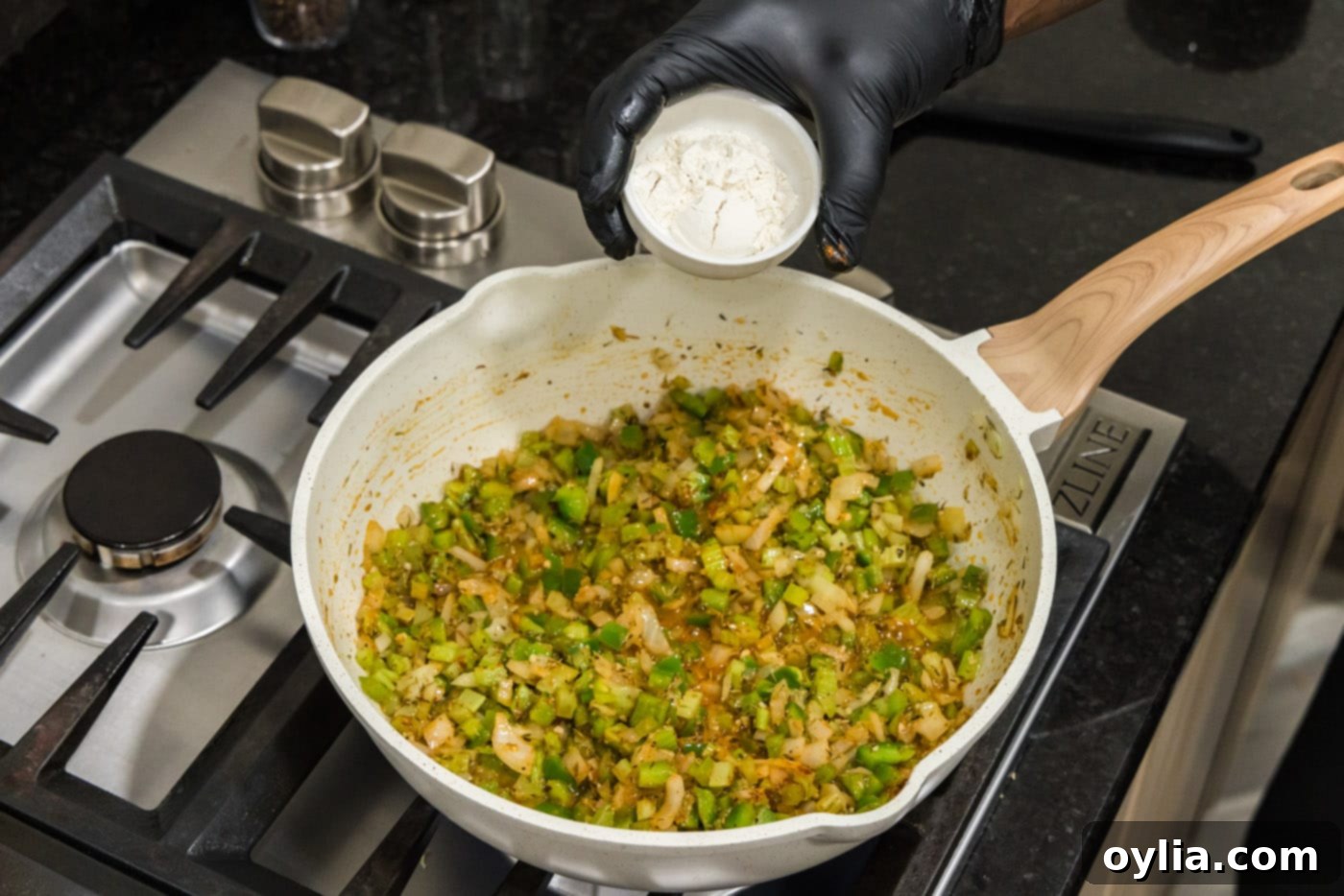 adding flour to skillet of cajun holy trinity and spices