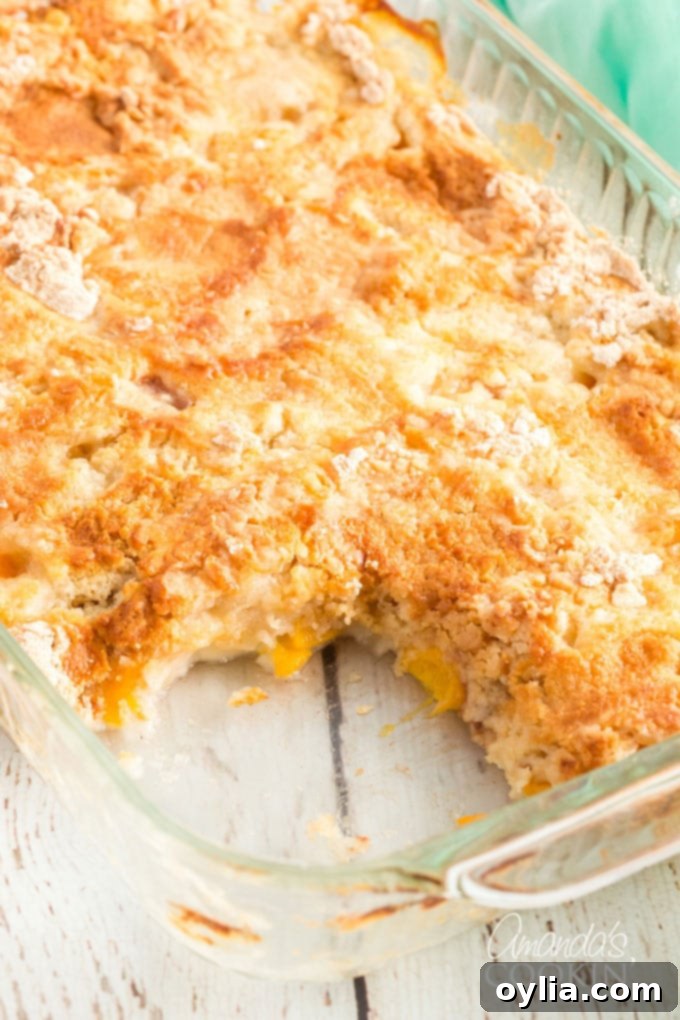 A baked peach dump cake with a generous slice already removed, showcasing its tender, golden crust and juicy peach filling.