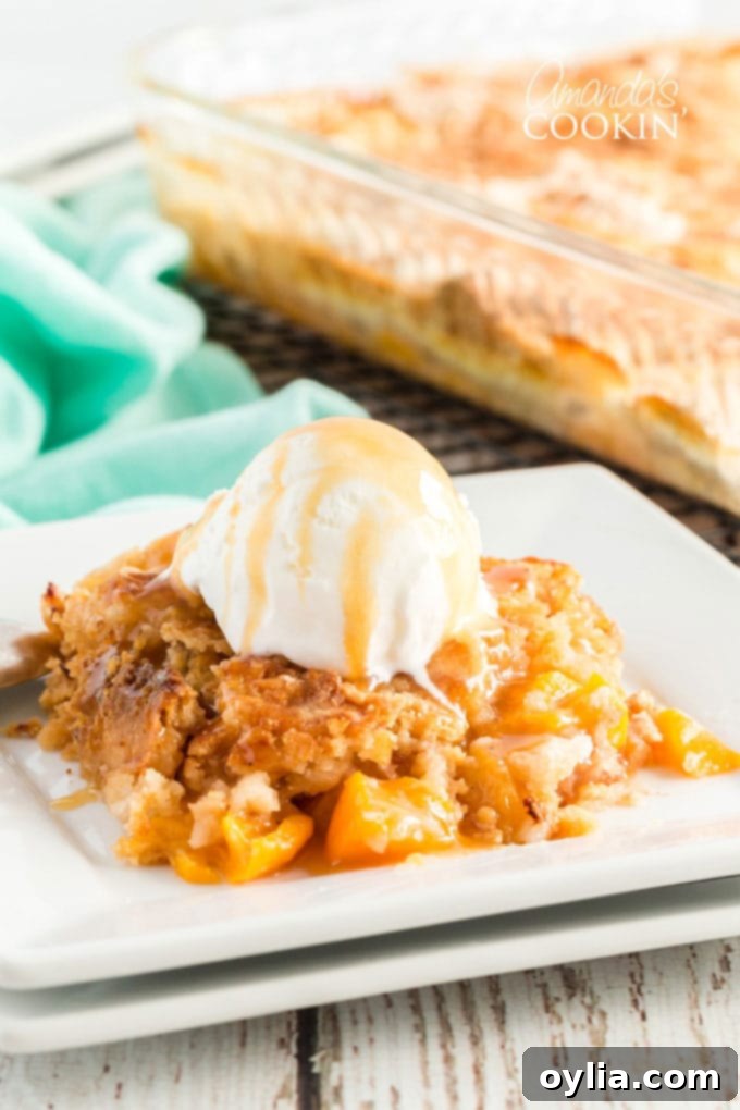 A generous serving of peach cobbler dump cake topped with creamy vanilla ice cream and drizzled with luscious caramel sauce, ready to be enjoyed.