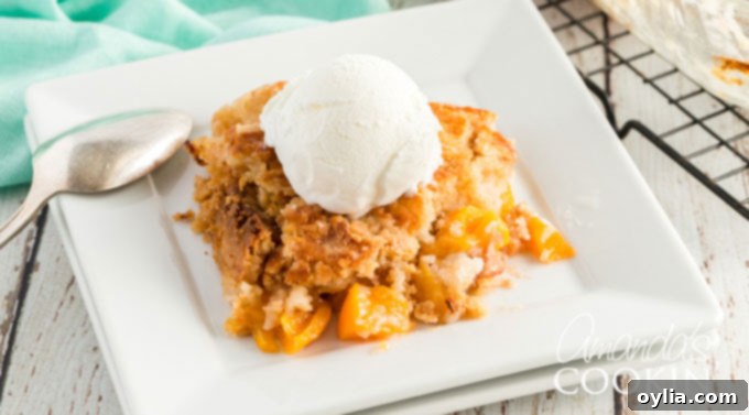 A perfect slice of peach cobbler, showcasing the tender fruit and golden, crumbly topping, sitting on a white plate ready to be enjoyed.