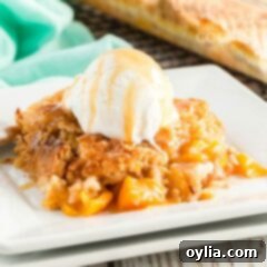A warm slice of peach cobbler dump cake with a scoop of vanilla ice cream melting on top, on a white plate.