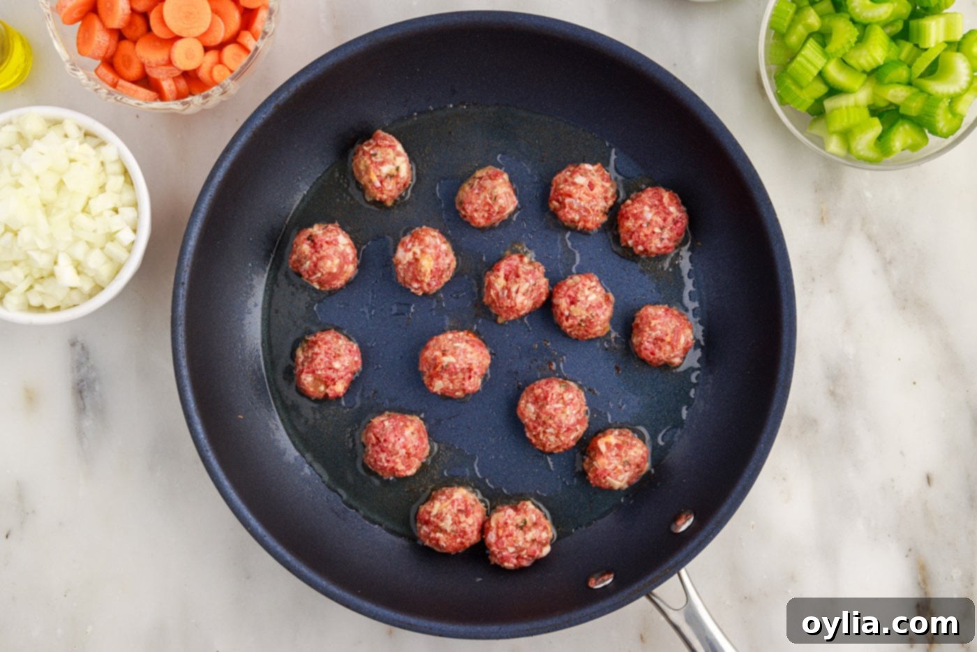 Italian meatballs searing in a skillet