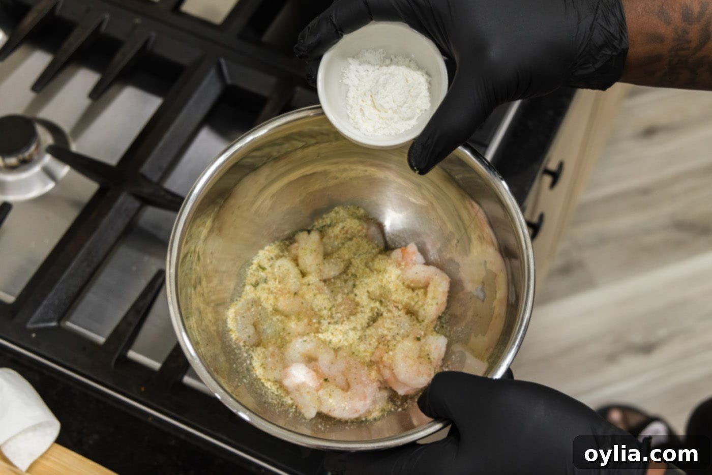 adding cornstarch to bowl with seasoned shrimp
