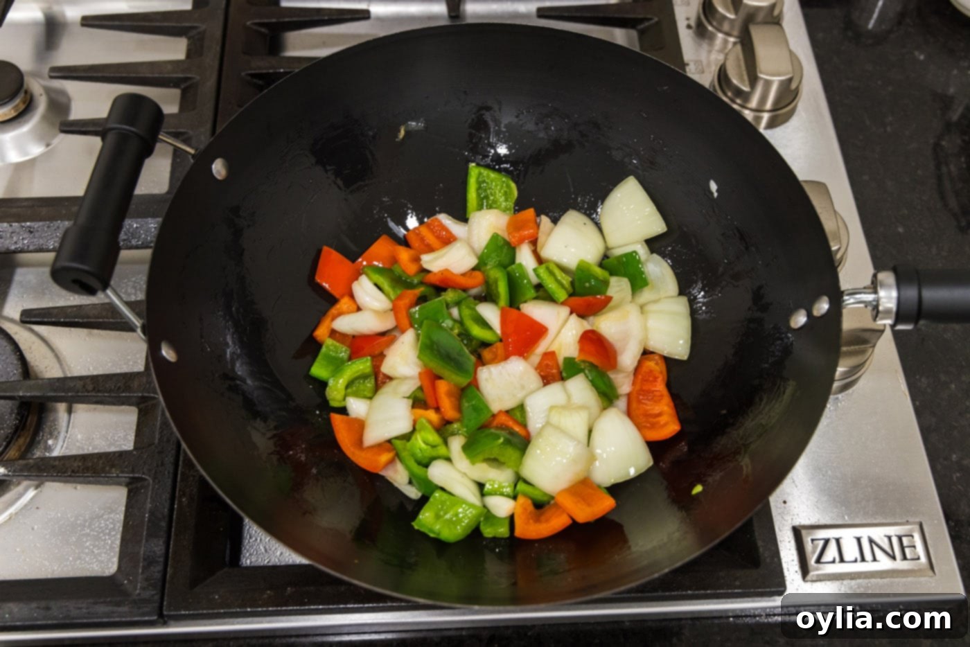 Chopped onion and bell peppers stir-frying in a wok