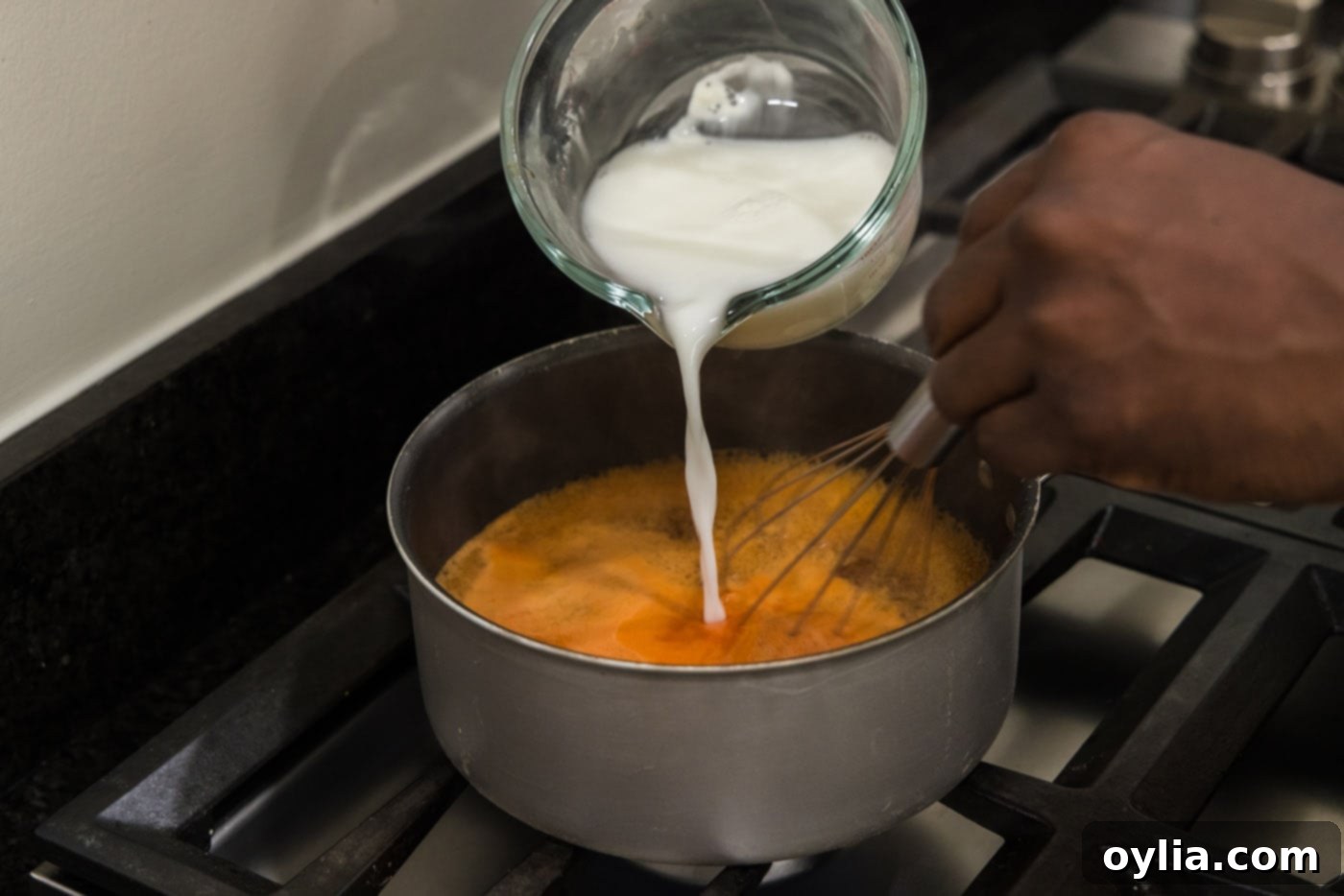 Pouring cornstarch slurry into bubbling sweet and sour sauce to thicken it