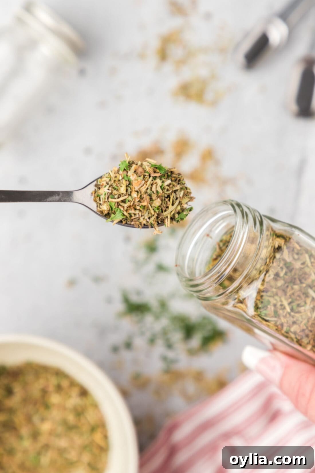 Classic Italian Herb Blend 3 A measuring spoon filled with rich, fragrant homemade Italian seasoning, pulled from a glass spice jar.