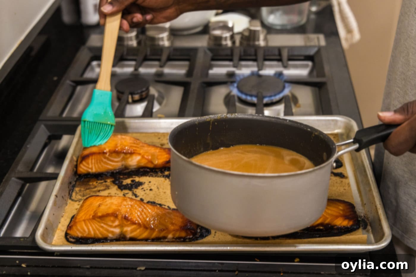 Basting salmon fillets with the rich miso glaze on a baking sheet