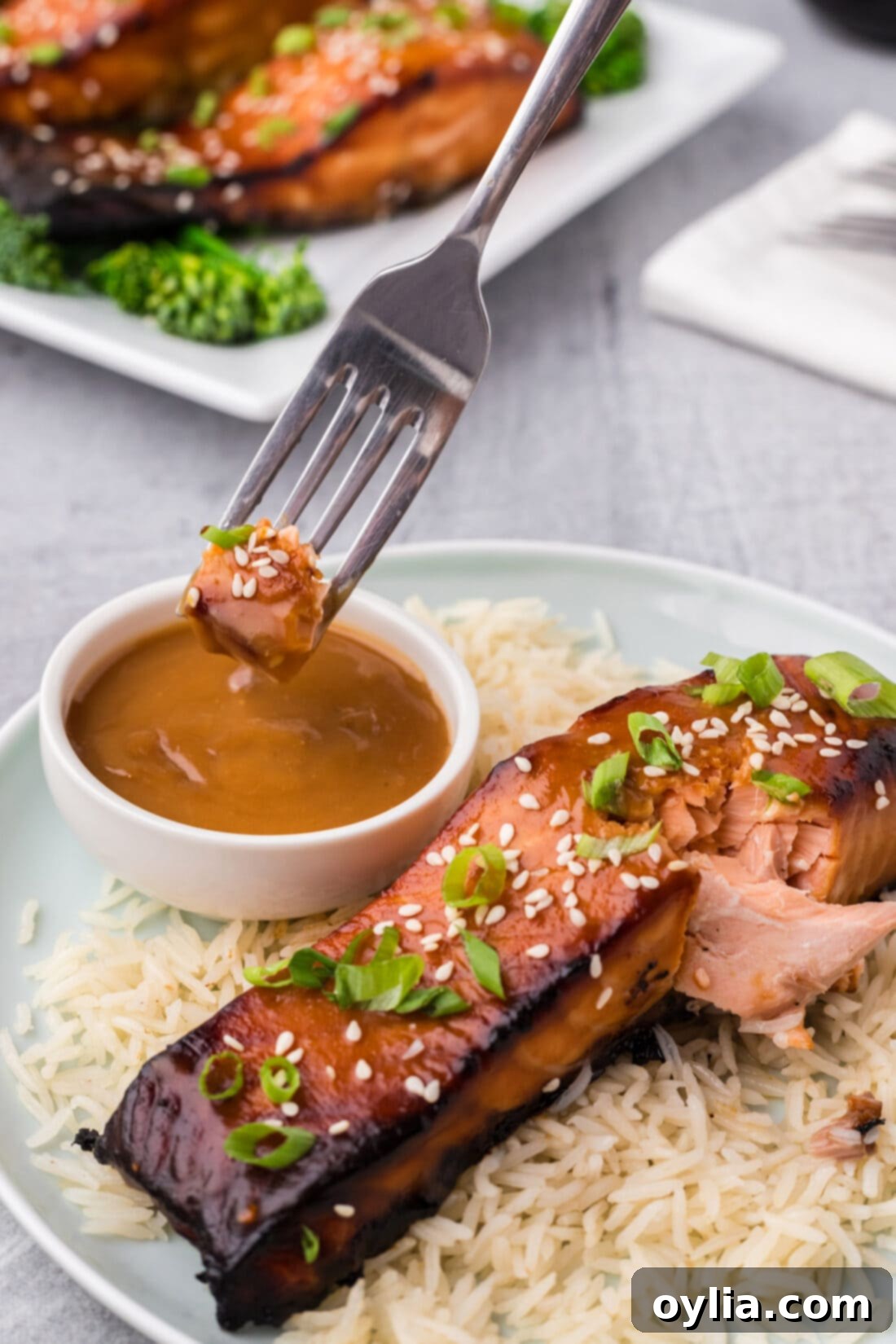 Piece of Miso Salmon being dipped into extra miso sauce, highlighting its glaze