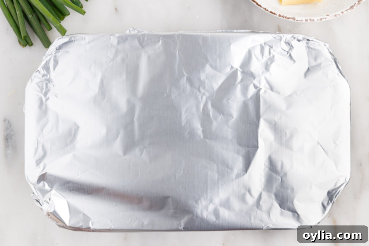 Buffalo chicken casserole dish covered with aluminum foil, ready for baking.