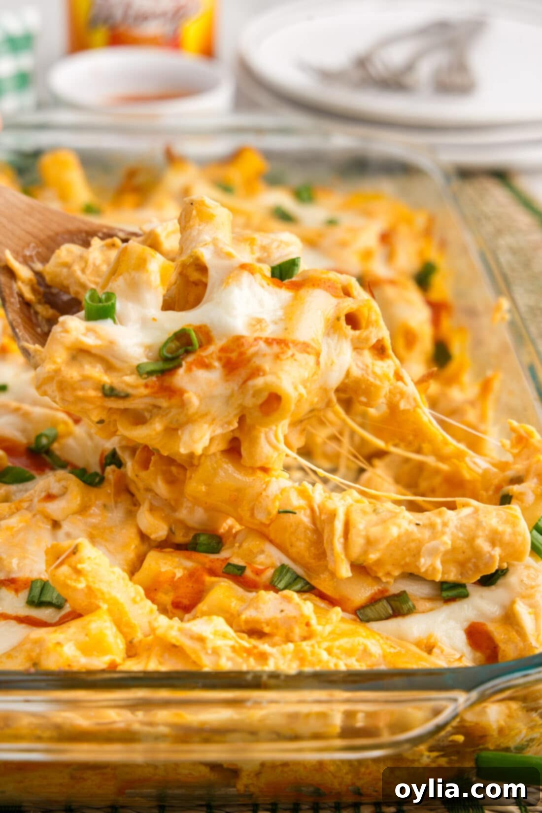 A spoonful of creamy Buffalo Chicken Casserole being lifted from the dish, showing melted cheese and pasta.