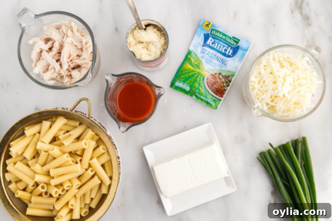 A flat lay of all the ingredients required to make Buffalo Chicken Casserole, including pasta, chicken, cheeses, and sauces.