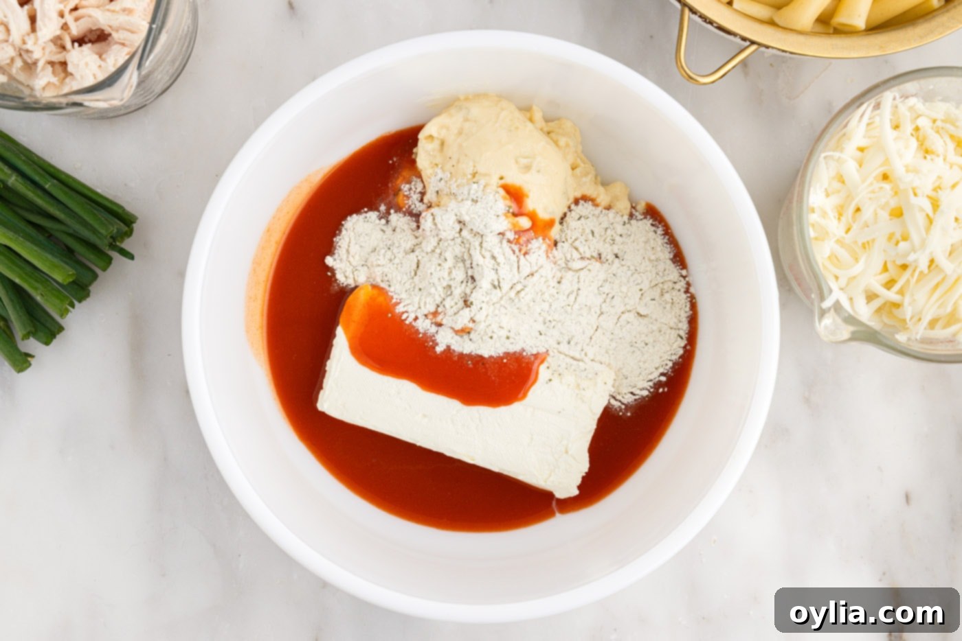 hot sauce, cream cheese, ranch seasoning mix, and cream of celery soup in a bowl, ready to be mixed