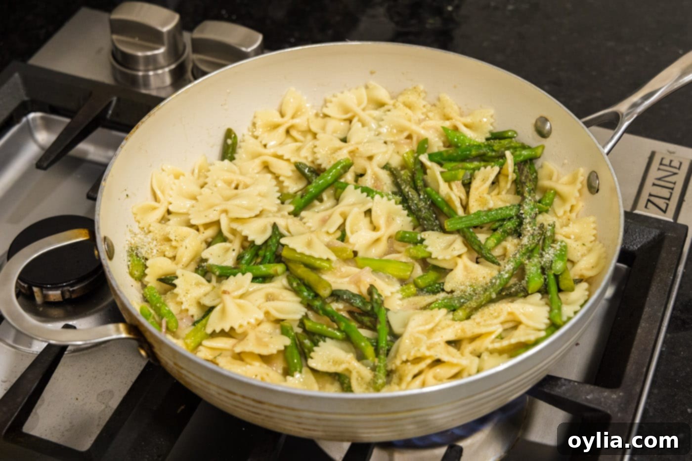 The finished asparagus pasta tossed and ready in the skillet, vibrant and coated in sauce.