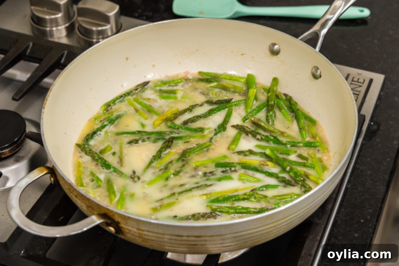 Cornstarch slurry being poured into the skillet to thicken the asparagus pasta sauce.