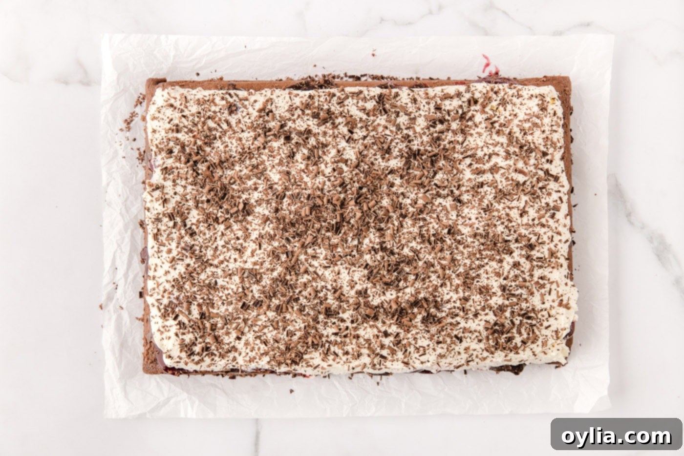 Chocolate shavings artfully scattered over the whipped cream topping of the Black Forest Poke Cake.