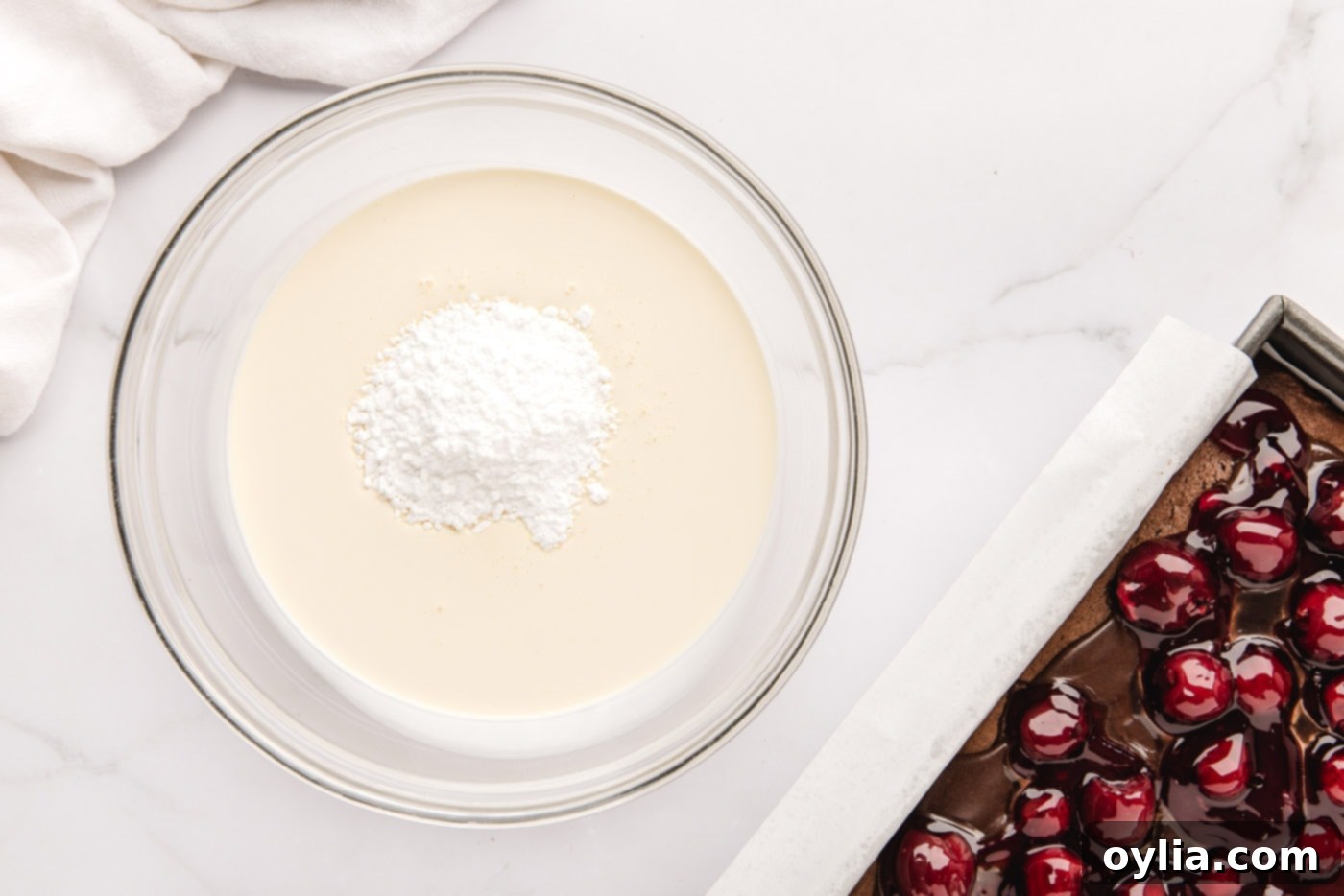 Heavy whipping cream and powdered sugar in a mixing bowl before being whisked.