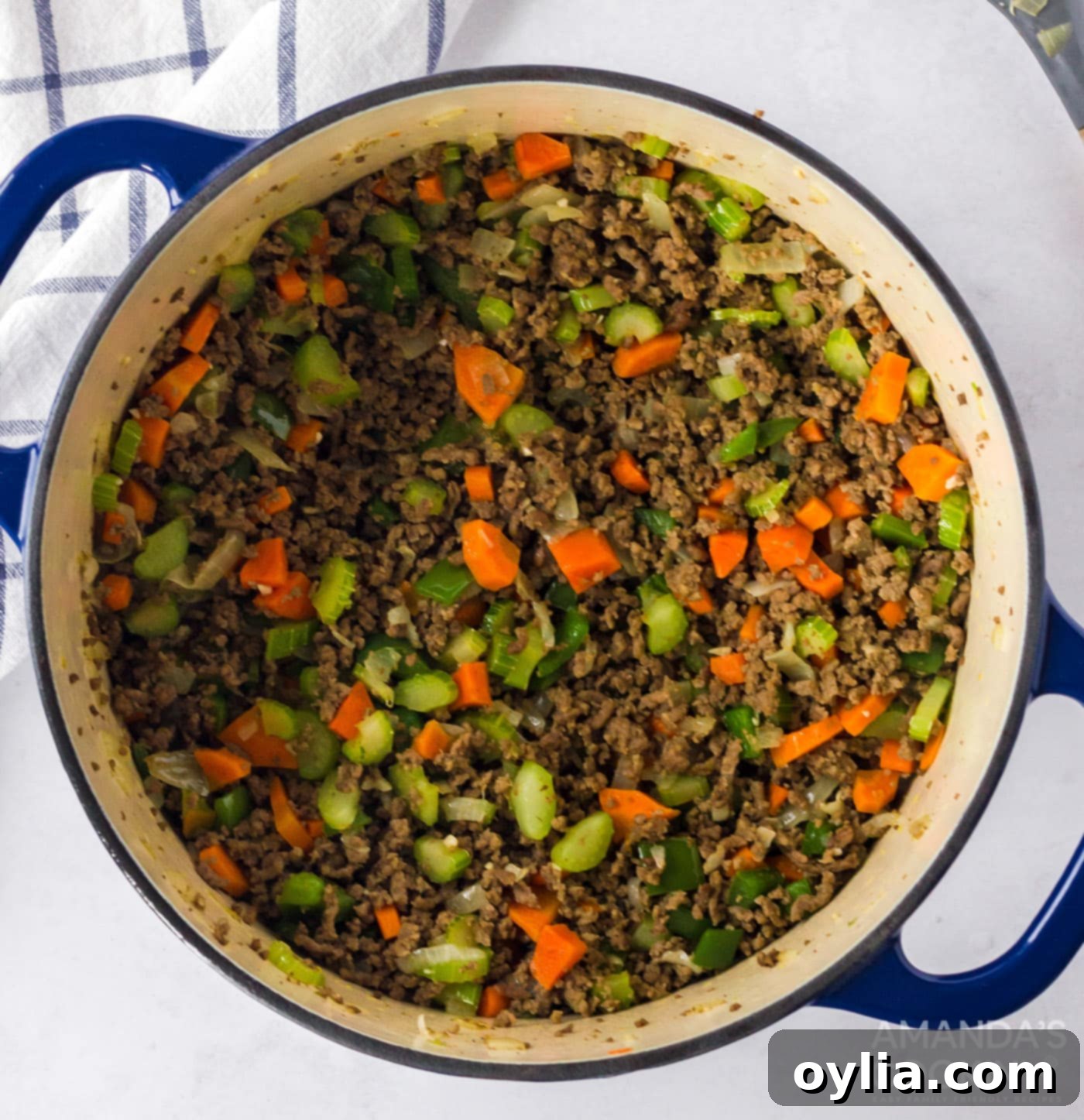 Ground beef, celery, carrot, onion, green bell pepper and garlic sautéing in a pot