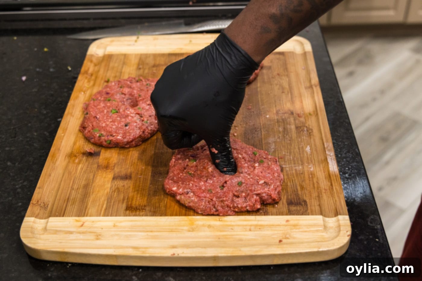 pressing thumb into center of bison burgers