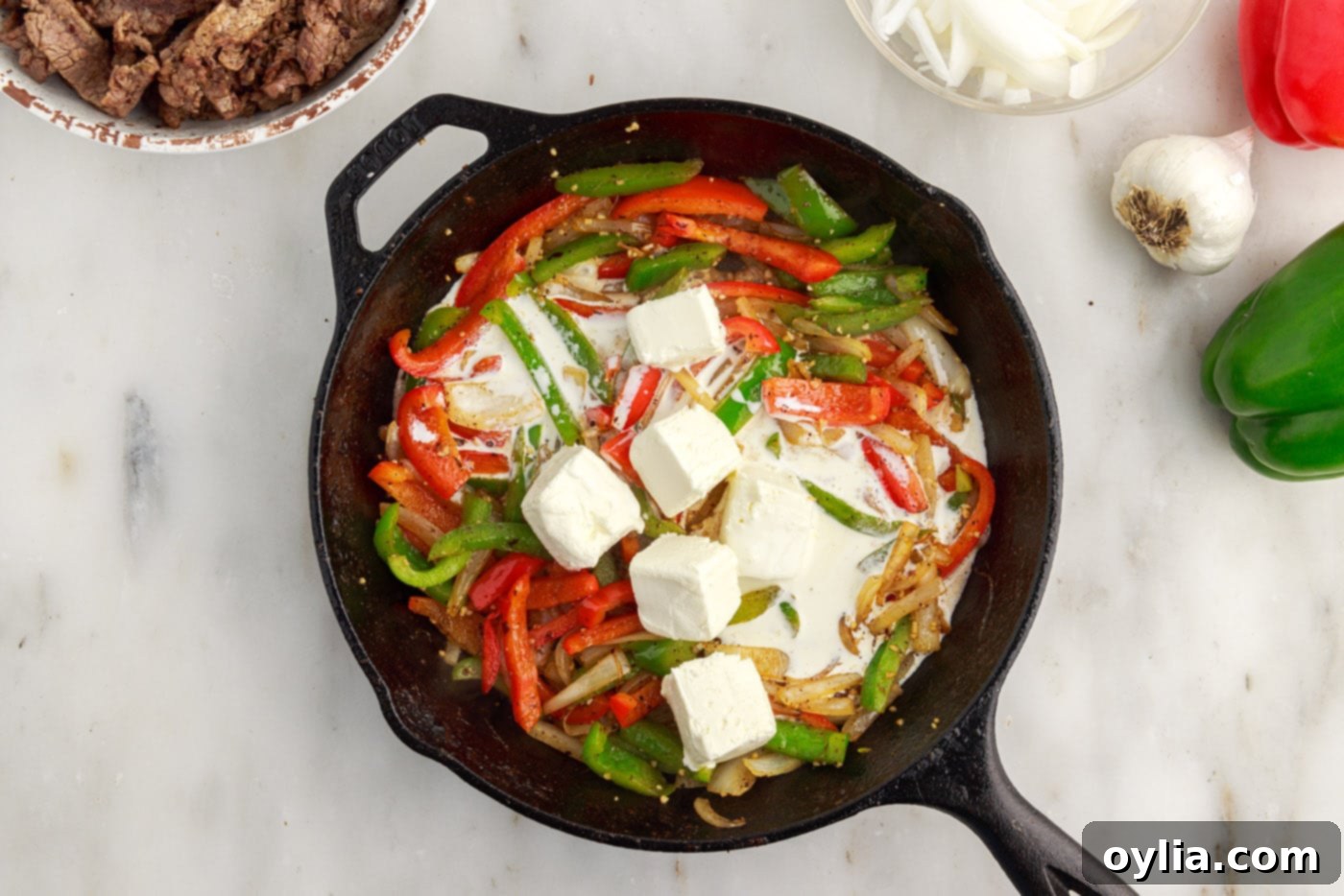 cream cheese and heavy cream added to skillet with bell peppers and onions