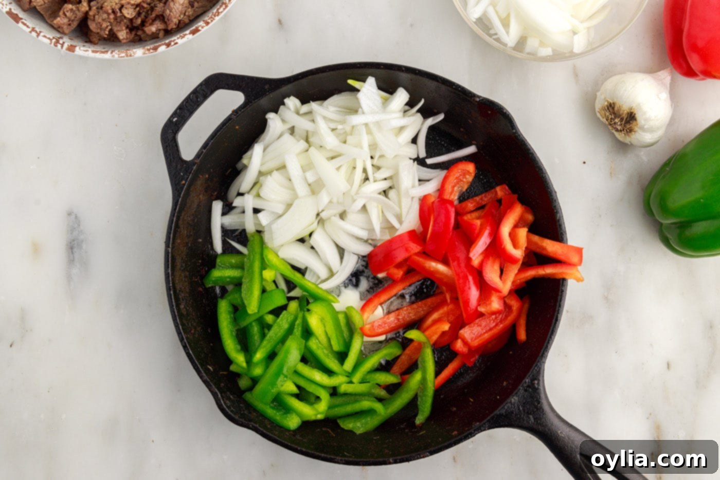 sliced bell peppers and onions in a cast iron skillet