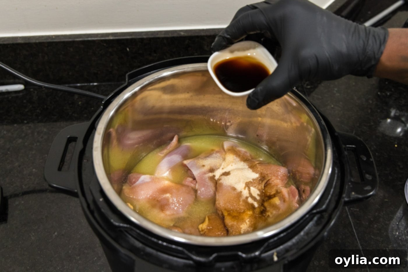 Adding Worcestershire sauce and liquid smoke to BBQ chicken in the Instant Pot.