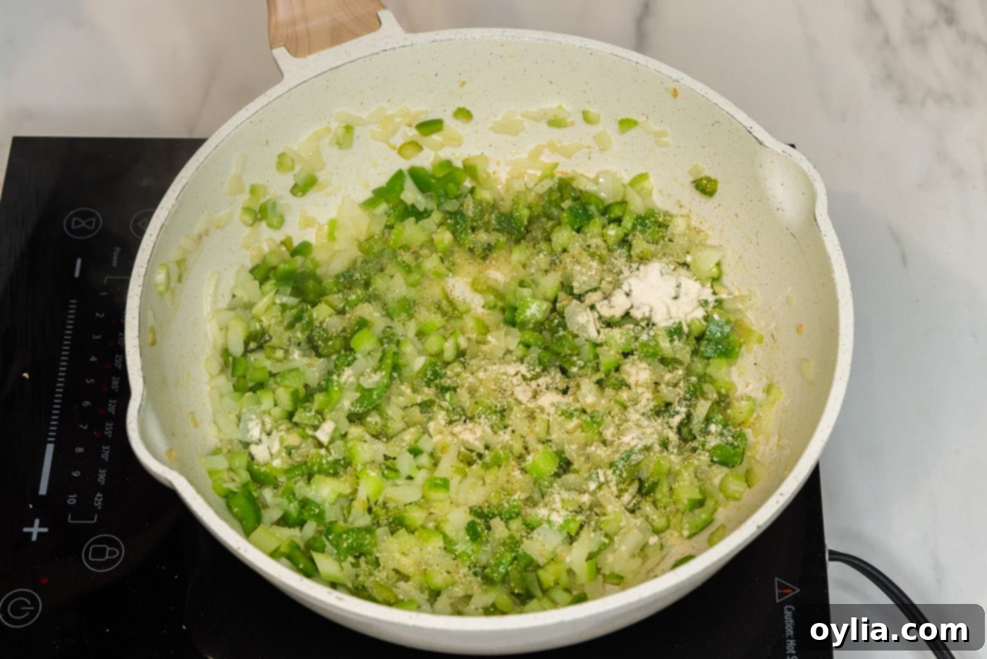 adding seasonings to skillet with celery, onion, and bell peppers