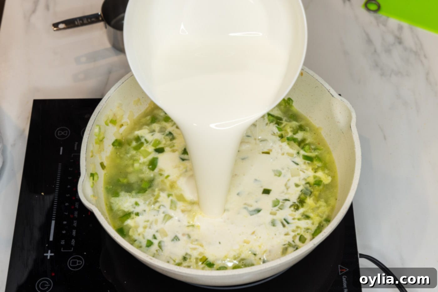pouring heavy cream into skillet with chopped sauteed vegetables