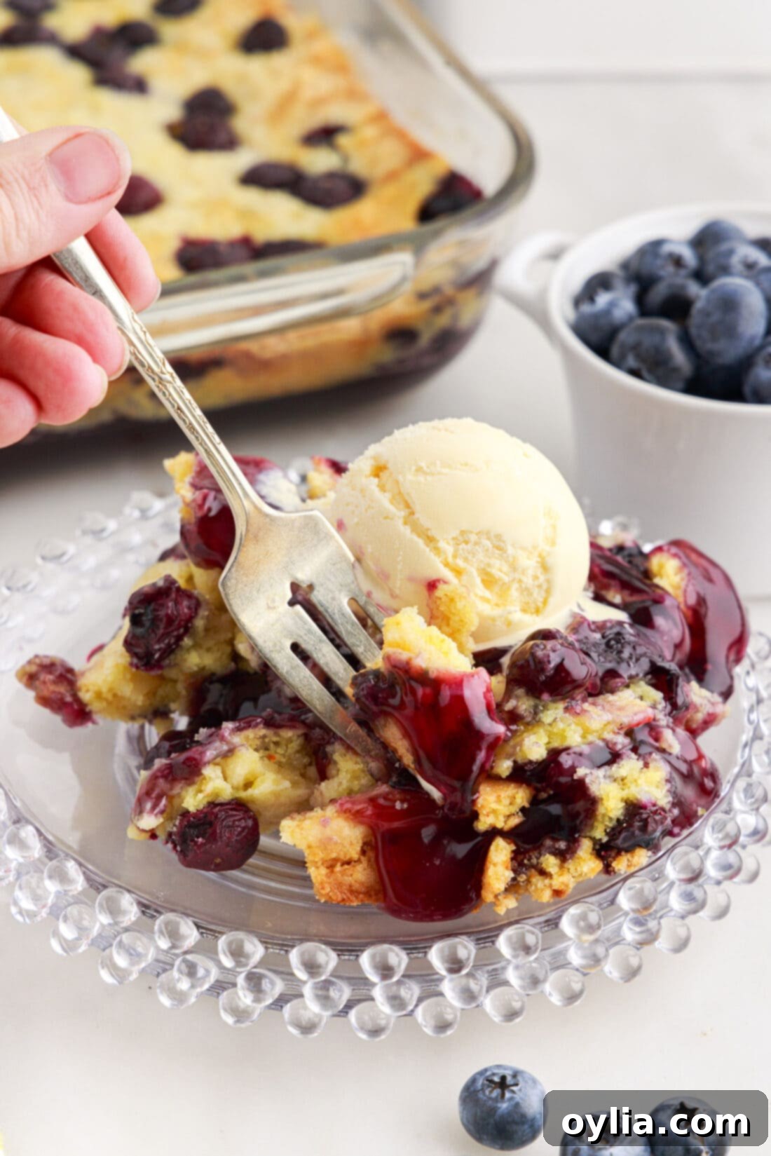 Fork dipping into a serving of Blueberry Dump Cake on a plate