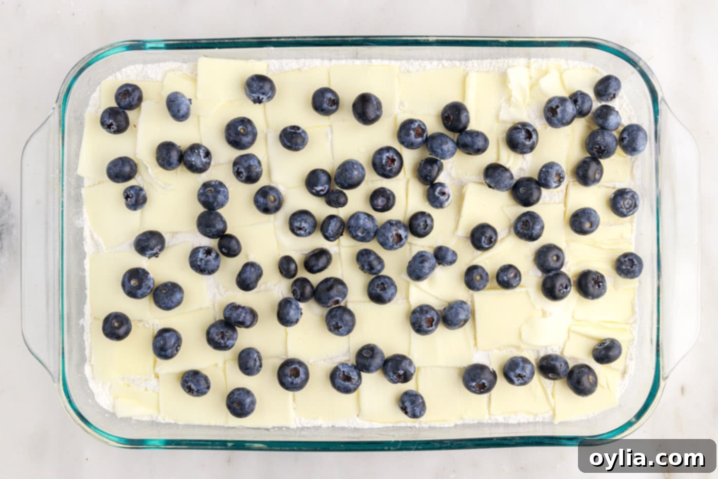 blueberry speckled on top of butter and cake mix in a baking dish