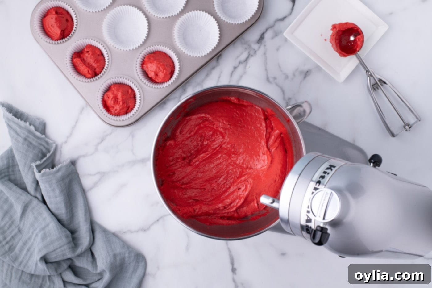 The fully mixed red velvet cupcake batter in a stand mixer bowl, showing its vibrant color