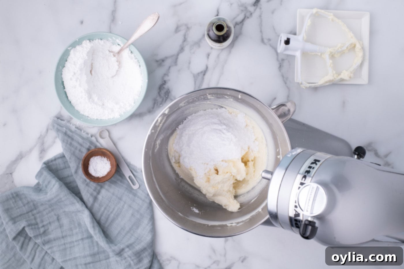 Gradually adding powdered sugar to cream cheese frosting in a mixer bowl