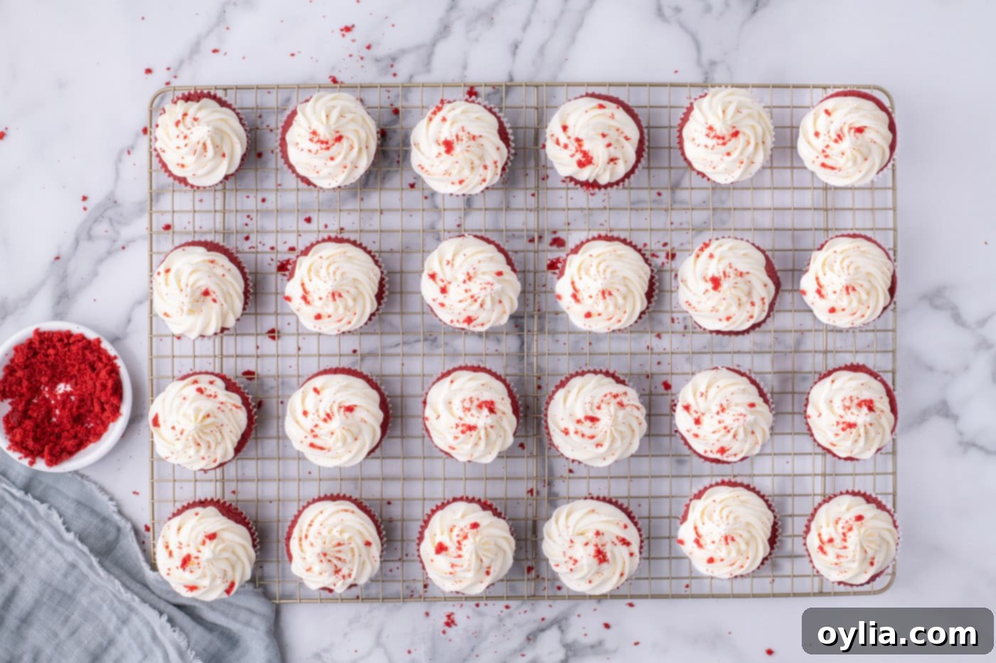 Overhead view of beautiful red velvet cupcakes topped with cream cheese frosting, cooling on a wire rack