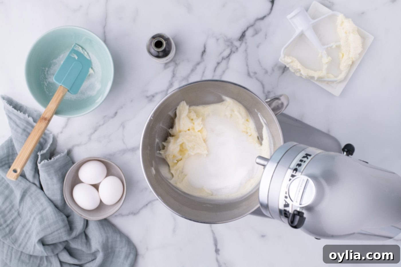 Granulated sugar being added to the creamed butter in a mixer bowl