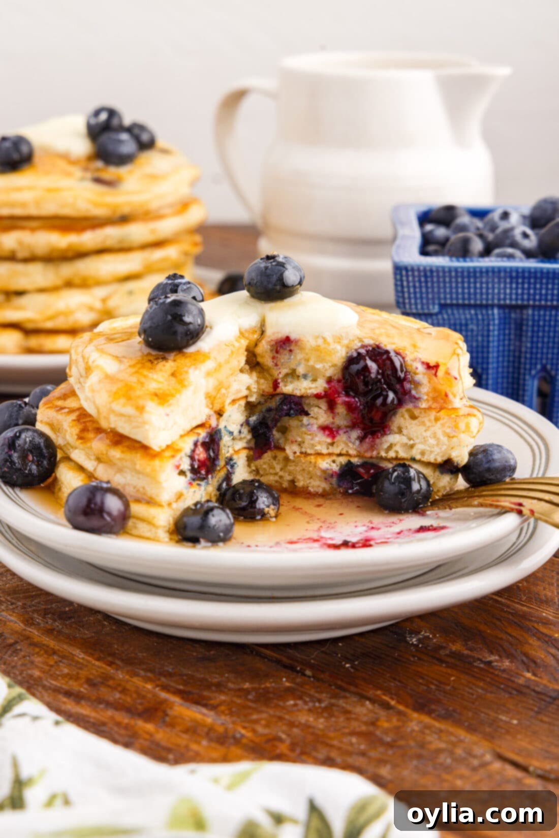 Berry Burst Pancakes 12 A stack of perfectly cooked blueberry pancakes on a plate, with a bite taken out, revealing the fluffy interior and melted blueberries, ready to be enjoyed.