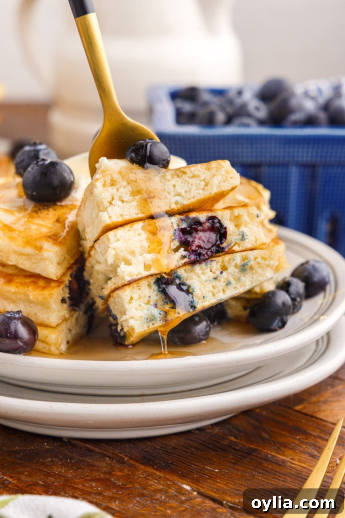 Berry Burst Pancakes 3 A close-up of a fork holding a piece of fluffy blueberry pancake, showing the tender interior and juicy berries.