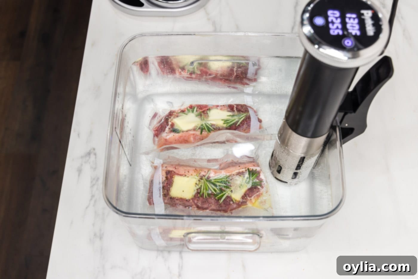Vacuum-sealed New York strip steaks fully submerged in a preheated sous vide water bath.