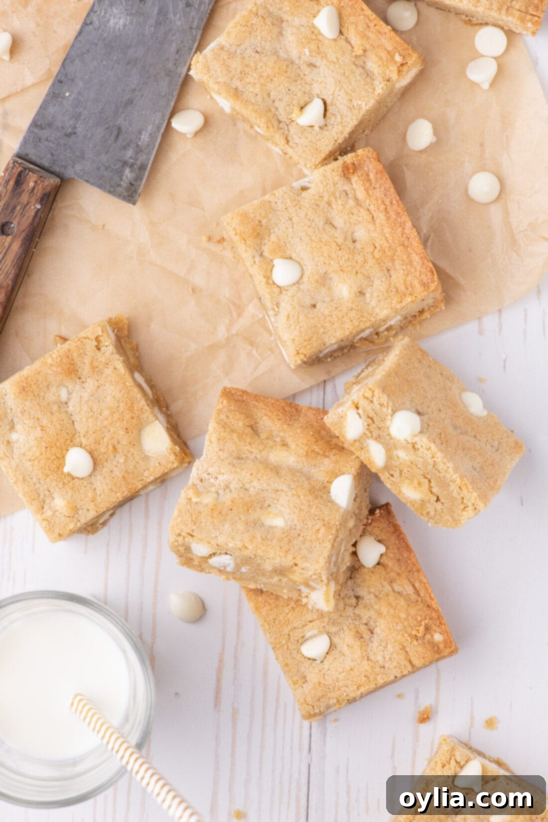 Chewy Golden Blondies 3 Blondies resting on parchment paper with a glass of milk