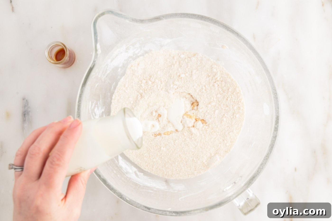 Adding vanilla extract and heavy whipping cream to the brown butter and powdered sugar mixture.