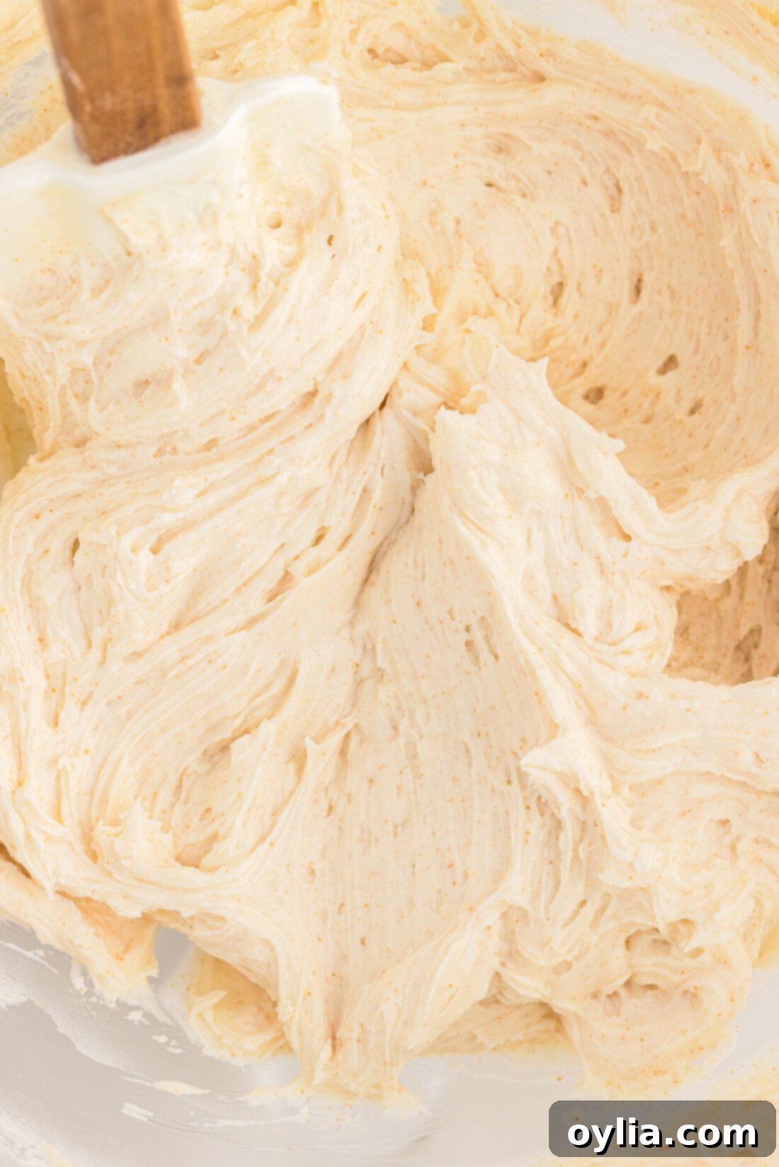 Close up photo of fluffy Brown Butter Frosting in a mixing bowl, showing its rich color and creamy texture.