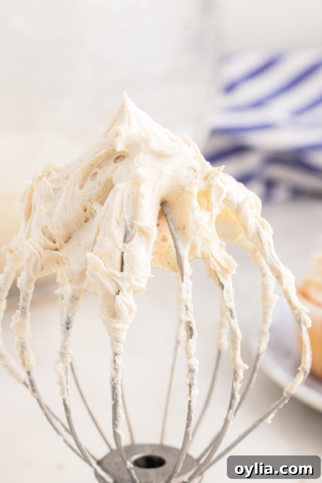 Close-up of brown butter frosting on a mixer whisk attachment, showing its creamy texture.