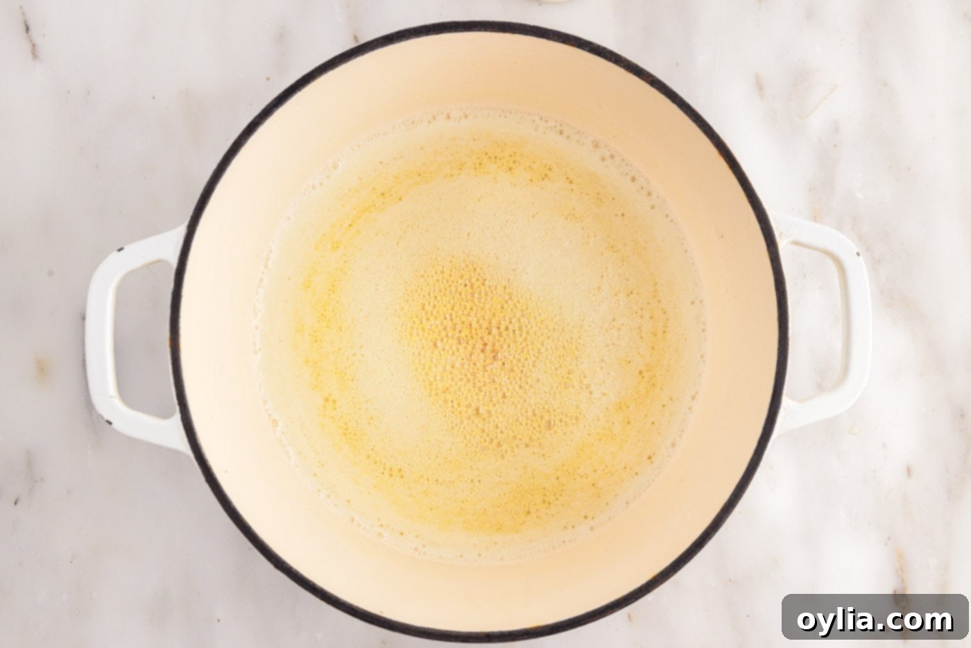 Melted butter simmering, beginning to foam in a saucepan.