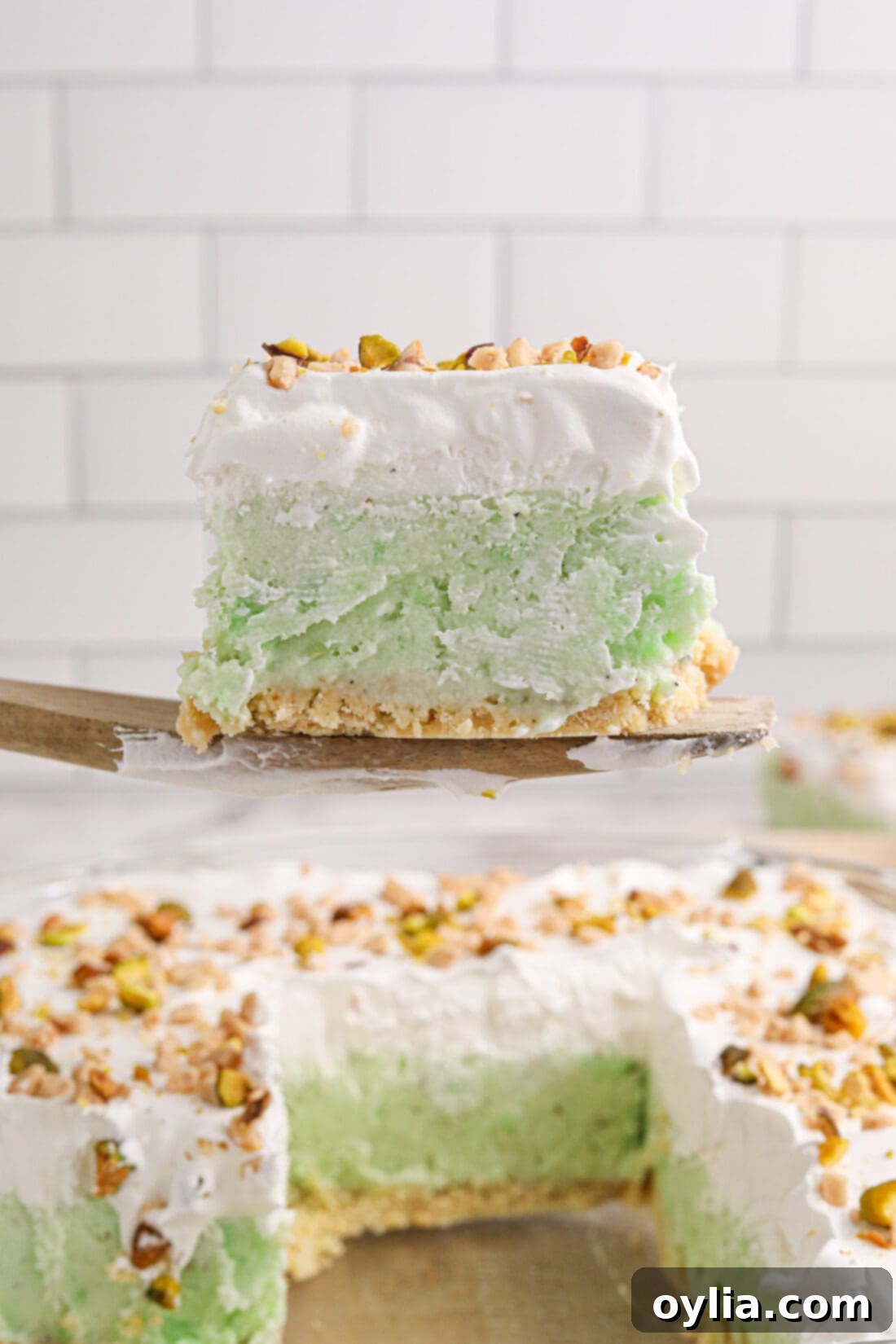 Ultimate Pistachio Ice Cream Cake 3 A delicious slice of Pistachio Ice Cream Cake being carefully lifted from the pan with a spatula, showcasing its beautiful layers.